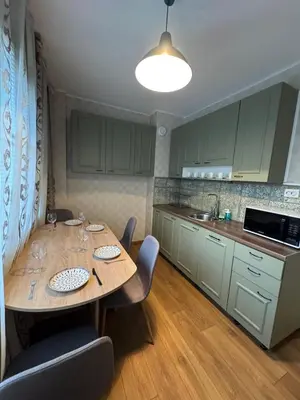 a kitchen with a wooden table with chairs and a kitchen with green cabinets at Cozy Corner in Nadezhda in Sofia