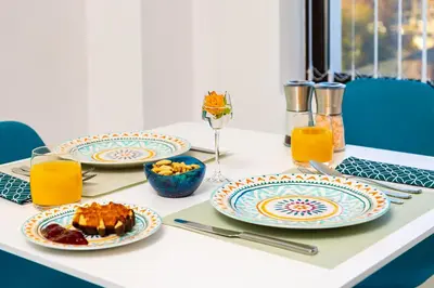 a table with plates of food and orange juice at Plovdiv Urban Gem Studio by Flat Mаnаger in Plovdiv