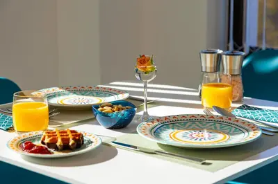 a table with plates of food and glasses of orange juice at Plovdiv Urban Gem Studio by Flat Mаnаger in Plovdiv