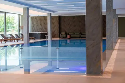 a pool in a hotel room with chairs and tables at Saint Sofia Golf Club, Hotel and SPA in Robertowo