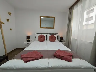 a bedroom with a bed with red pillows on it at Апартаменти Белчини in Dobrinishte