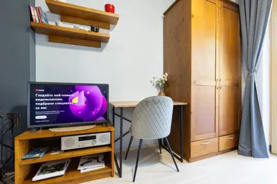 a room with a tv and a table with a chair at 2-room Forest Retreat - Fireplace, Veranda, BBQ, Views in Bansko