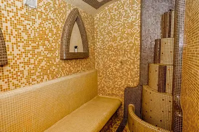 a tiled bathroom with a bench and a mirror at Хотел Валентино 2 in Dobrinishte