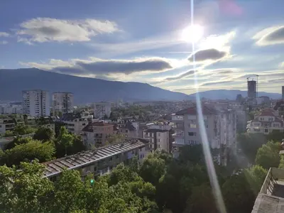 a view of a city with the sun in the sky at Апартамент Sofia View in Sofia