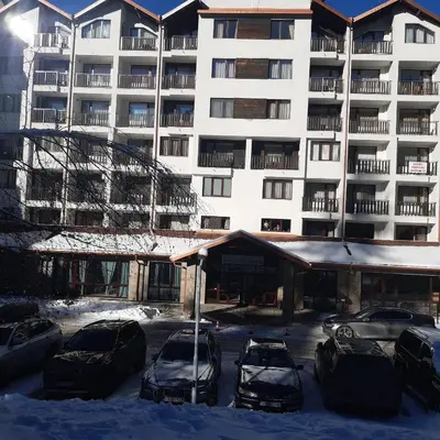 a snow covered parking lot in front of a building at ТЕС Боровец Гарденс in Borovets
