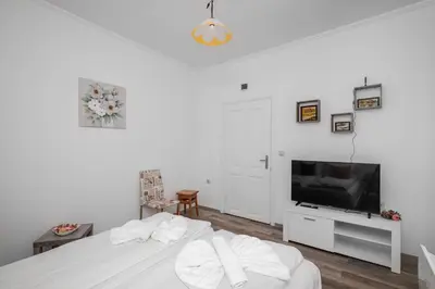 a white bedroom with a bed and a flat screen tv at Central 1BD Next to Womens Market and Sofia's Gems by Flat Mаnаger in Sofia