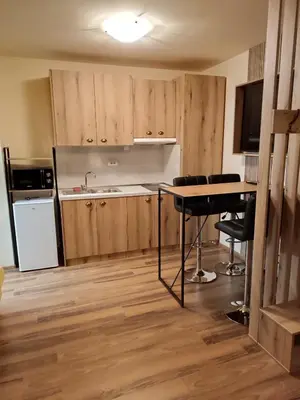 a kitchen with wooden cabinets and a table and chairs at Апартаменти Pamporovo Dream в Гранд Ризорт Пампорово in Pamporovo