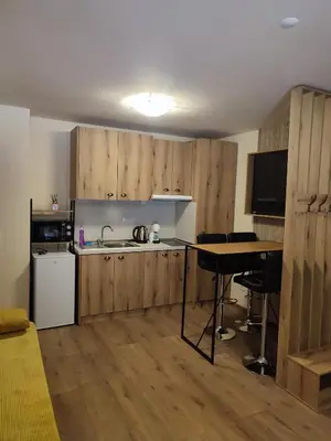 a kitchen with wooden cabinets and a sink and a table at Апартаменти Pamporovo Dream в Гранд Ризорт Пампорово in Pamporovo
