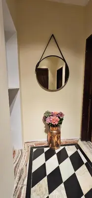 a mirror and a vase with flowers in a room at Elegant and cozy apartment in Sofia