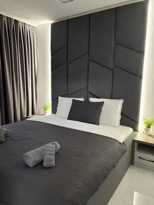 a bedroom with a large bed with a black headboard at Center Park Apartment in Sandanski