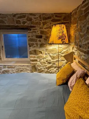 a bedroom with a bed with a stone wall at Ta Petrina Cottage in Selishte