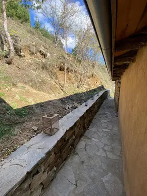 a stone wall next to a building with a bench at Ta Petrina Cottage in Selishte
