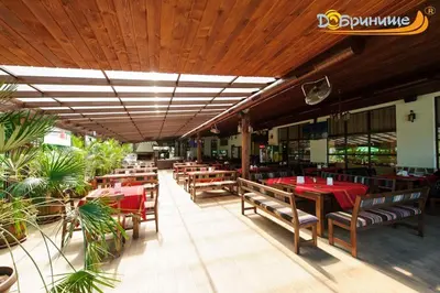 a restaurant with wooden tables and chairs with red table cloth at Хотел Добринище in Dobrinishte