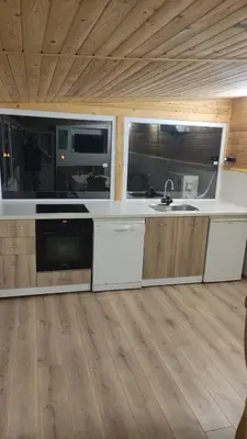 a kitchen with white counters and a wooden floor at Guest House Mihalkovo in Mikhalkovo