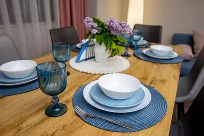 a wooden table with plates and bowls and a vase of flowers at Saphi Apt in Sandanski