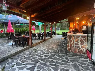 a restaurant with tables and chairs and a stone patio at Парк-хотел Родопи in Churen