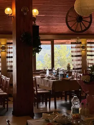 a dining room with tables and chairs and a large window at Парк-хотел Родопи in Churen