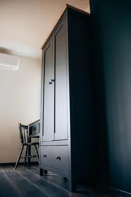 a white cabinet in a room with a chair at Wonderland Rooms for Rent in Sofia