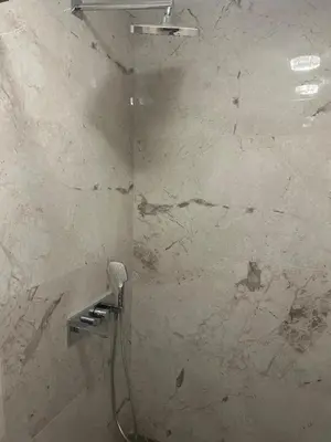 a bathroom with a shower with a white marble wall at Cozy and comfortable panorama park Entrance E not K in Plovdiv