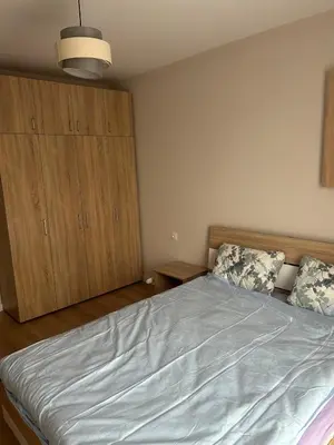 a bedroom with a bed and a wooden cabinet at Cozy and comfortable panorama park Entrance E not K in Plovdiv