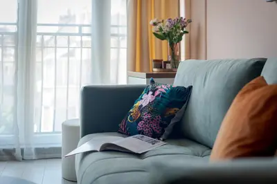 a blue couch with a book sitting on it at Maison Colorée - Bright And Cozy Home by Metro And Mall in Sofia