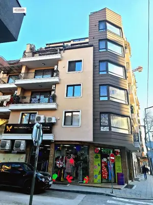 a tall building on a city street with a car in front at Cozy Home In Central Plovdiv in Plovdiv