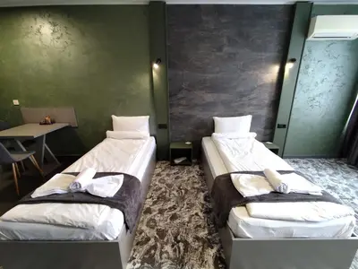 two beds in a room with a table at RCR Einstein studios 3 in Sofia