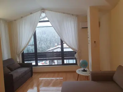 a living room with a large window and a couch at Apartment Sunny in Pamporovo