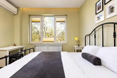 a bedroom with a large white bed and two windows at Serene Living in the Heart of Plovdiv by Flat Mаnager in Plovdiv
