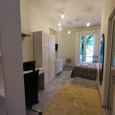 a bedroom with a bed and a desk and a window at NDK Central Home in Sofia