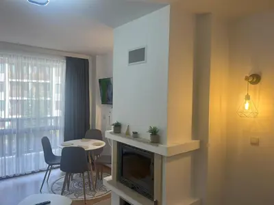 a living room with a fireplace and a table and chairs at Nest by the Peaks Apartment in Bansko in Bansko
