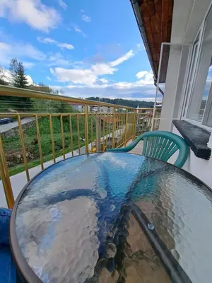 a glass table on a balcony with a view at Къща за гости ЖАНИ in Zmeitsa