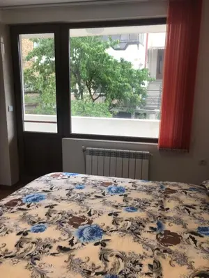 a bedroom with a bed with a floral bedspread and a window at При Бети in Sandanski