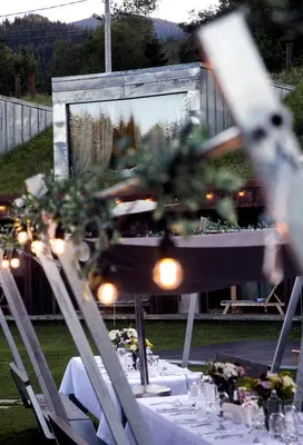 a long table with white tables and chairs with lights at Хотел Гела in Gela