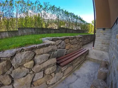 a stone retaining wall with a bench in a yard at Guest Rooms Lencho in Anton