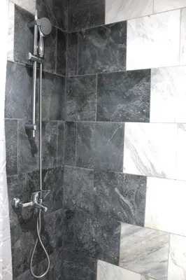 a shower with a black and white tile at Apartment Near NDK Biairbnb in Sofia