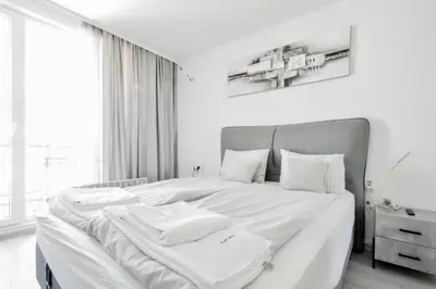 a white bedroom with a large bed with white sheets and pillows at Crème Lux - Elegant 1BD in Manastirski Livadi by Flat Manager in Sofia
