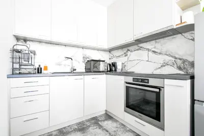 a white kitchen with marble walls and white cabinets at Crème Lux - Elegant 1BD in Manastirski Livadi by Flat Manager in Sofia