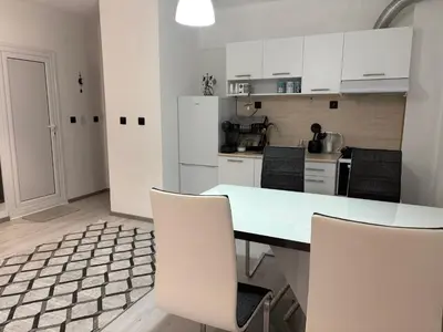a kitchen with white cabinets and a table and chairs at Трушеви in Sandanski