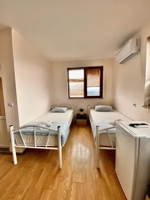 two beds in a room with wooden floors and a window at Helena Hostels in Kostinbrod