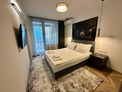 a small bedroom with a bed and a large window at Milea apartments in Sofia