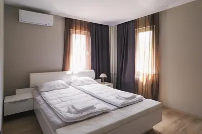 a white bed in a room with two windows at Iztok House Apartment in Sofia