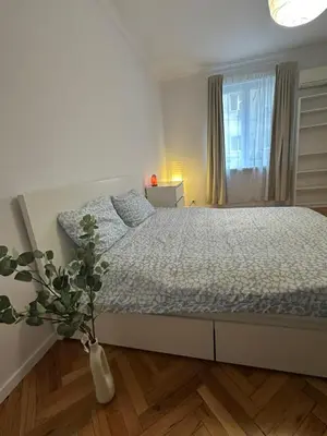 a white bedroom with a bed and a vase with a plant at Apartament 151 in Sofia