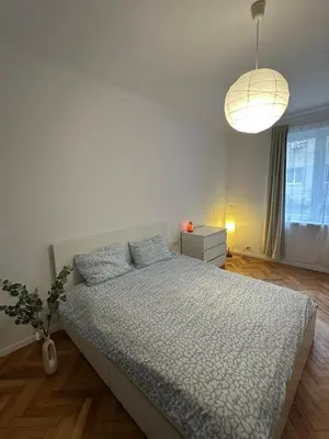 a white bedroom with a bed and a lamp at Apartament 151 in Sofia