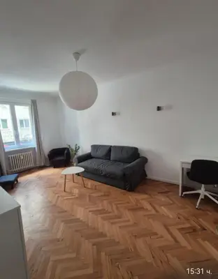 a living room with a black couch and a wooden floor at Apartament 151 in Sofia