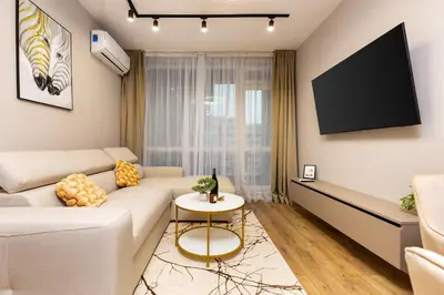a living room with a white couch and a tv at 1BR Modern and Cozy Apartment with Free Street Parking in Plovdiv
