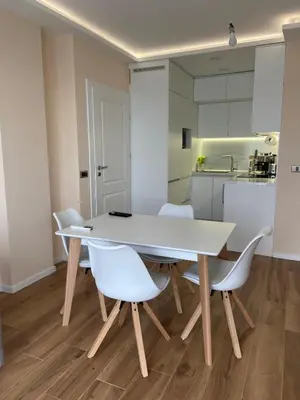 a white dining room table with white chairs and a kitchen at Sofia Park View Apartment in Sofia