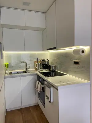 a white kitchen with white cabinets and a sink at Sofia Park View Apartment in Sofia