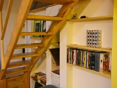 a wooden staircase with bookshelves and books at Anna's downtown loft in Plovdiv