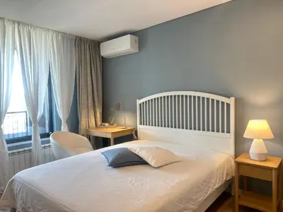 a bedroom with a white bed and a chair and a window at Апартамент В 48 в Сграда МОНА in Sofia
